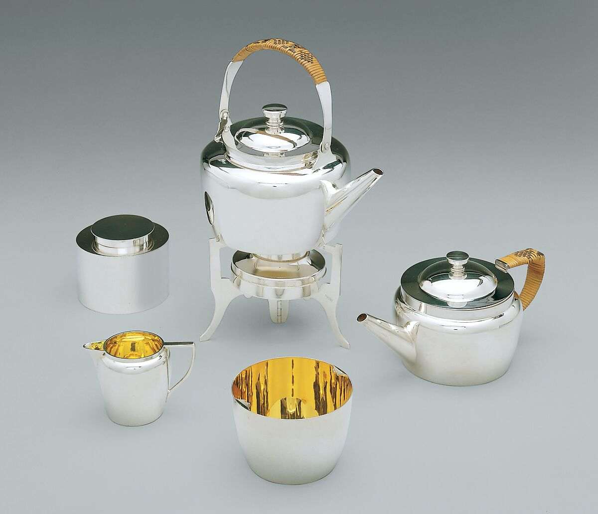 Silver-plated tea vessels with bamboo handles, arranged as a compact set.