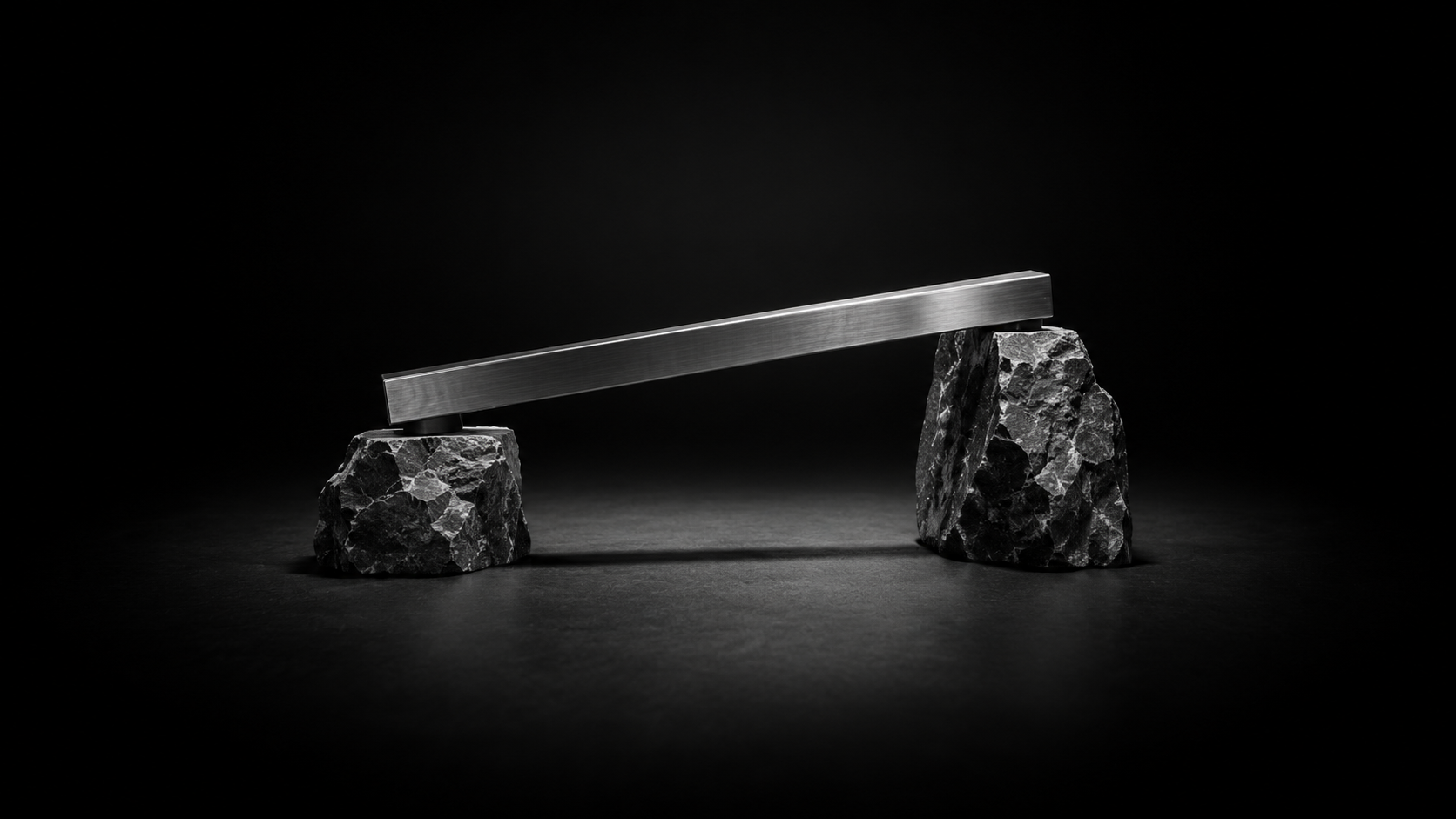 A straight metal beam rests across rough stone supports of unequal height.