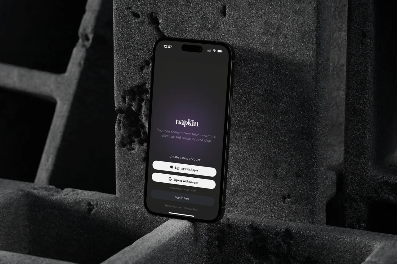 A iPhone 16 displays the Napkin app sign-up screen with options to sign up using Apple or Google.