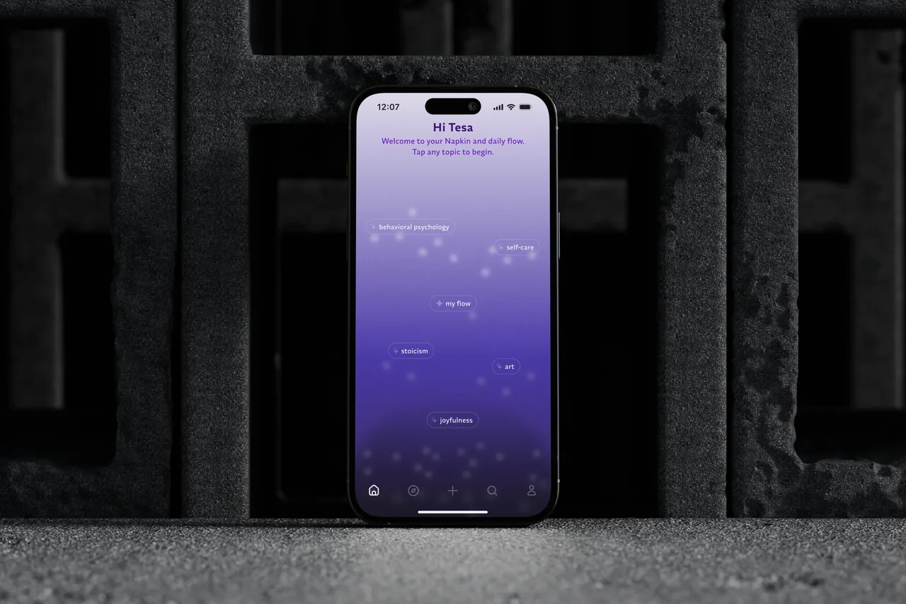 iPhone 16 displaying Napkin app "Home Screen" for topic exploration with topics like behavioral psychology, self-care, and joyfulness on a purple gradient background.