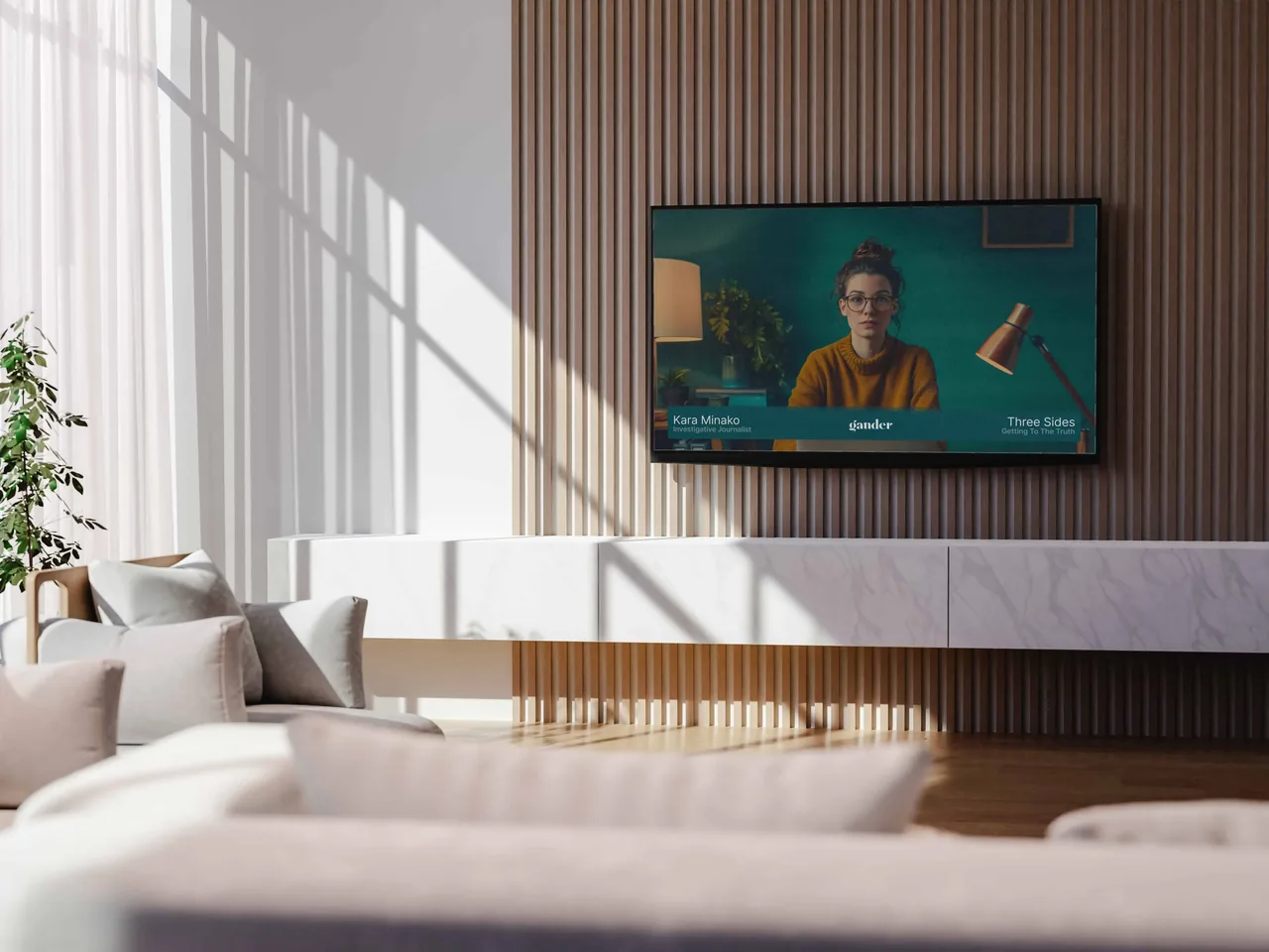 A modern living room with a wall-mounted TV showing a Gander news broadcast featuring a woman reporter in a mustard sweater in front of a green set..
