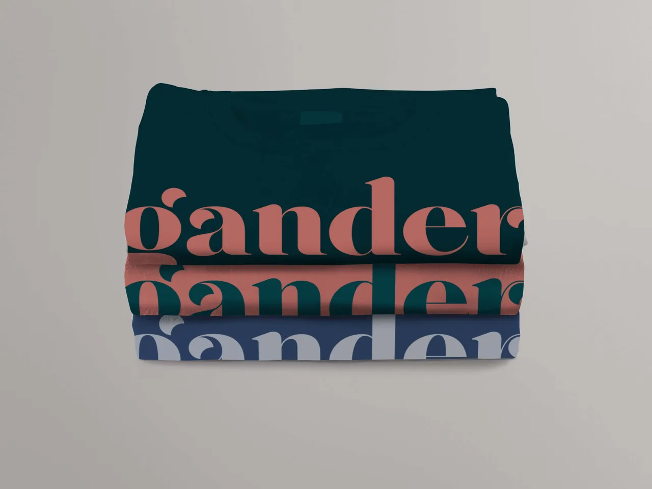 Three folded t-shirts stacked, each in a color from the Gander palette, featuring the Gander wordmark printed in bold contrasting colors.