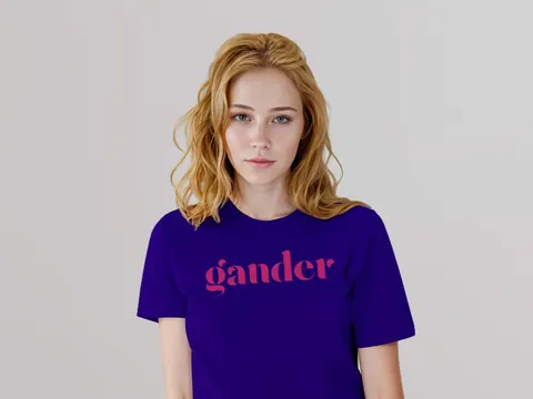 A woman with blonde hair wearing a purple shirt with the Gander logo in a contrasting bold pink color.