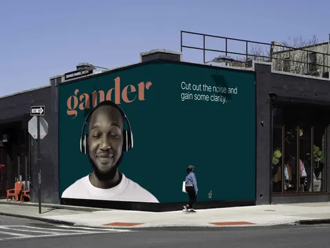 A Gander billboard shows a man wearing headphones with eyes closed and text saying "Cut out the noise and gain some clarity."